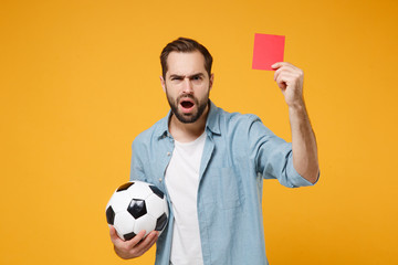 Shocked bewildered young man in blue shirt posing isolated on yellow orange wall background. People...