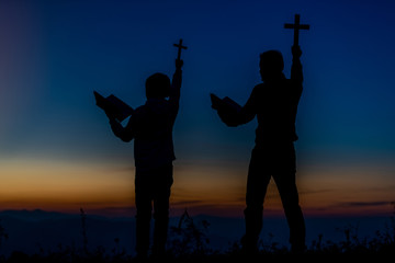 Prayer is a Christian family that is praying in the Bible and lifting a cross over a Christian with a sunset light background. Christian concept