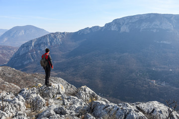 Fototapeta premium Adventurous man is standing on top of the mountain and enjoying the beautiful view. A man stands on the edge of a cliff in Sicevo Gorge, Serbia. Travel Lifestyle emotional concept