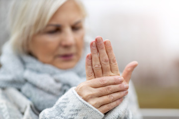 Senior woman with arthritis rubbing hands