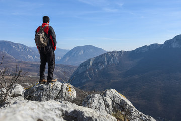 Adventurous man is standing on top of the mountain and enjoying the beautiful view. A man stands on...