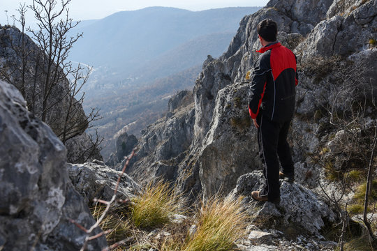 Adventurous man is standing on top of the mountain and enjoying the beautiful view. A man stands on the edge of a cliff in Sicevo Gorge, Serbia. Travel Lifestyle emotional concept