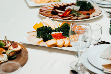 Restaurant table with many dishes with food on it. Food Table Celebration Delicious Party Meal Concept. A lot of food. Served for wedding, anniversary, other holiday. Banquet dishes in the restaurant