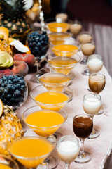Festive table with cold exotic alcoholic beverages, cocktails and fruits. Celebration or other event. Strawberyy, kiwi, pineapple and other fruits on the table