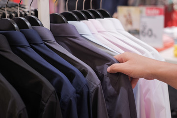 Cropped Hand Of Man choosing Men's shirts in clothing store