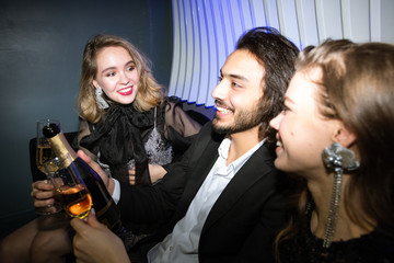 Happy glamorous girls and young man with champagne enjoying party