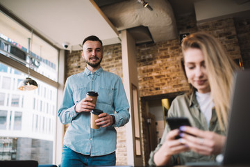 Young modern man bringing coffee to woman in cafe