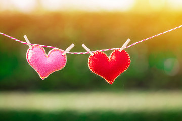 A red heart and pink heart hang with clip on the rope in the public park, Valentines day with love concept. - Powered by Adobe