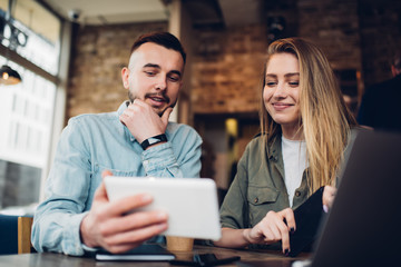 Cheerful couple watching tablet in cafe