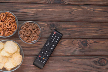 Chips, croutons, snacks. TV remote on the background of a wooden table. leisure. Leisure.