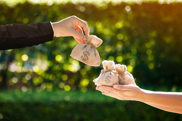 Businessman and a woman hands hold a money bags in the public park for loans to planned investment in the future concept.