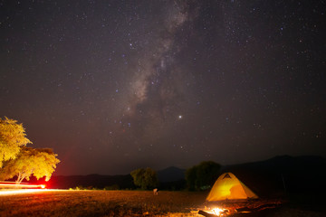 Landscape of the milky way galaxy with yellow tent camping over the  mountain at Kanchanaburi province ,Thailand.
