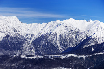 Fototapeta premium Panoramic view of winter peaks of mountains covered snow. Natural landscapes with Caucasus mountain. Rosa Khotor ski resort.