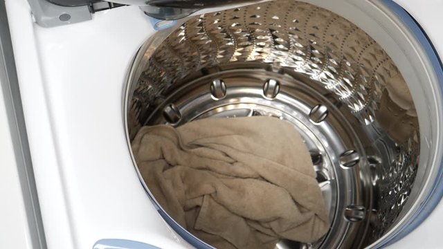 Load laundry into a washing machine and add soap 4K