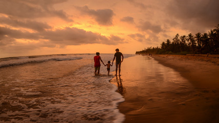 A healthy couple enjoying with their kid during a beautiful evening at the beach