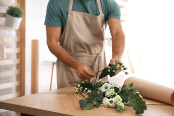 Florist making beautiful bouquet at table in workshop, closeup