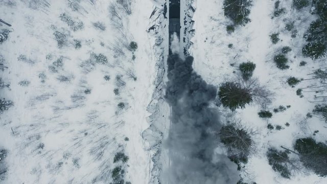 Aerial view black smoke from steam train in winter forest