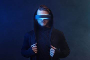 Young man in hoodie on virtual reality background. Guy using VR helmet. Augmented reality, future...