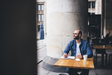 Adult poet writing at table in pavement cafe