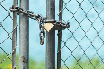 A metal gate is chained and locked to a fence