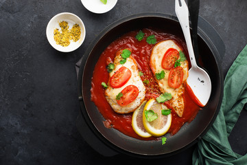 Baked chicken breast with cheese and tomato slices in a juicy tomato sauce on a baking sheet. Top view. Healthy eating,