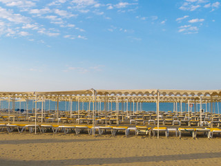 Empty sandy beach, no people. Mediterranean sea and blue sky, sun canopy is out of service. Low season. Beach without people. The end of the holiday season.