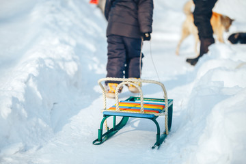 Fototapeta na wymiar kid going up on a hill pulling color sledge.
