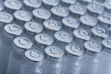 Glass medical ampoule vial for injection. Medicine is dry white drug penicillin powder or liquid with of aqueous solution in ampulla. Close up. Bottles ampule with aluminum cap on backgrounds gray.