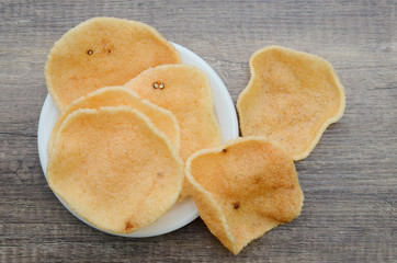 Pile of crunchy prawn cracker in a white plate on a wooden board