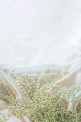 Defocused luxury silk background with a string of pearls. Delicate pastel shade. Pastel colors, concept of comfort and sexuality.