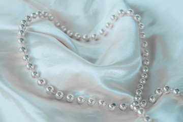 Defocused luxury silk background with a string of pearls. Delicate pastel shade. Pastel colors, concept of comfort and sexuality.