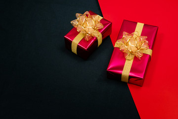 Top view of black gift box with red and black ribbons isolated on red and black background. Shopping concept boxing day and black Friday sale composition..