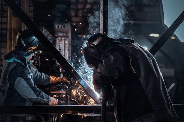 Man is working at metal factory, he is welding a piece of rail using special tools.