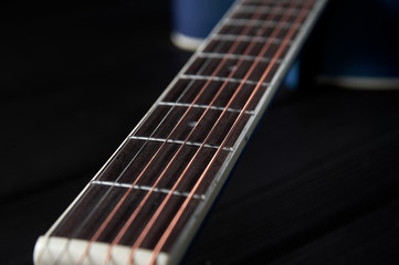 guitar neck with strings close-up on a black wooden background