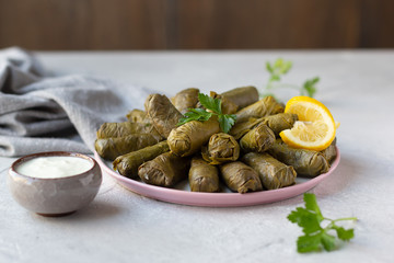 Dolma served with homemade yogurt and decorated with lemon slice. Azerbaijani and Turkish cuisine, grape leaves stuffed with minced meat and rice