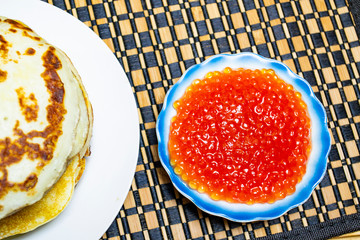 a stack of pancakes for Shrovetide, red caviar with pancakes on a table for a celebration of Shrovetide, selective focus