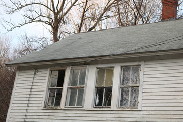 old historic abandoned New England house with broken windows and peeling paint