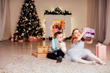 Fototapeta na wymiar the little boy and girl open Christmas presents Christmas tree new year's Eve family celebration