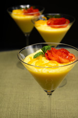 Vanilla Pudding with lemon and strawberry garnish in Martini glass with black background.