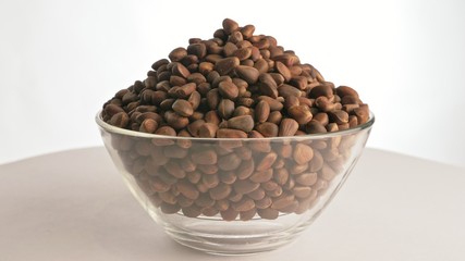 Pine nut rotate are on a table in a plate. Snack in transparent dish on an isolated white background are spinning moving. Delicious and healthy protein-rich diet food.