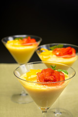 Vanilla Pudding with lemon and strawberry garnish in Martini glass with black background.