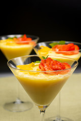 Vanilla Pudding with lemon and strawberry garnish in Martini glass with black background.