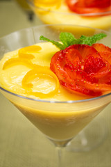Vanilla Pudding with lemon and strawberry garnish in Martini glass with black background.