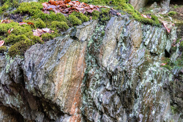 Massive Felswand aus Schiefergestein mit Felsvorsprüngen, grünem Moos, schroffen Kanten und steilen Klippen zeigt ein Kletterparadies für Free Climbing, Kletterer und Wanderer durch felsiges Gebirge