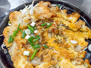 Crispy fried oyster pancake in hot plate . Oyster omelette or Fried clams . Thai food in hot pan with crispy flour and egg Popular manu Thai Cuisine. Delicious food on the sidewalk.