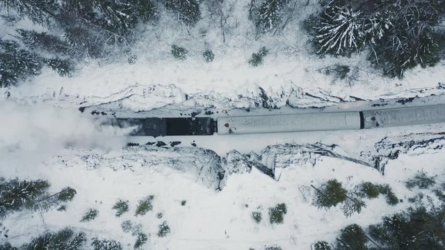 Aerial top down view steam train running backward in winter forest