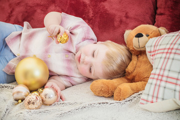  baby with Christmas balls and toys on sofa indoor