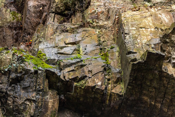 Massive Felswand aus Schiefergestein mit Felsvorsprüngen, grünem Moos, schroffen Kanten und steilen Klippen zeigt ein Kletterparadies für Free Climbing, Kletterer und Wanderer durch felsiges Gebirge