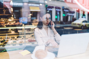Female freelancer explaining laptop data during phone conversation
