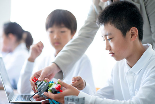 先生にプログラミングの勉強を教わる小学生